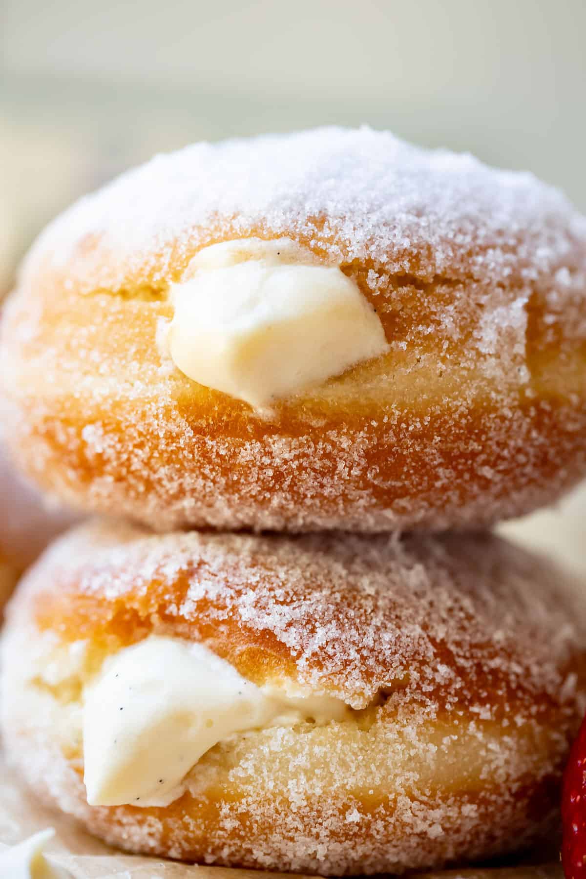 two stacked homemade donuts puffy with Bavarian cream filling and sugar rolled.