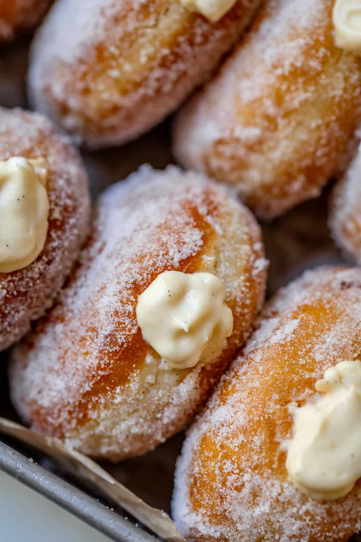 view of angled homemade donuts filled with Bavarian cream on a tray.