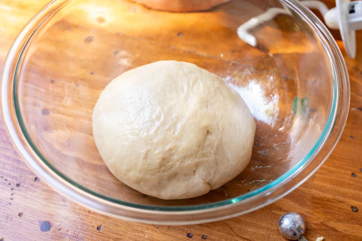 ball of Bavarian cream donut dough rising in a greased glass bowl.