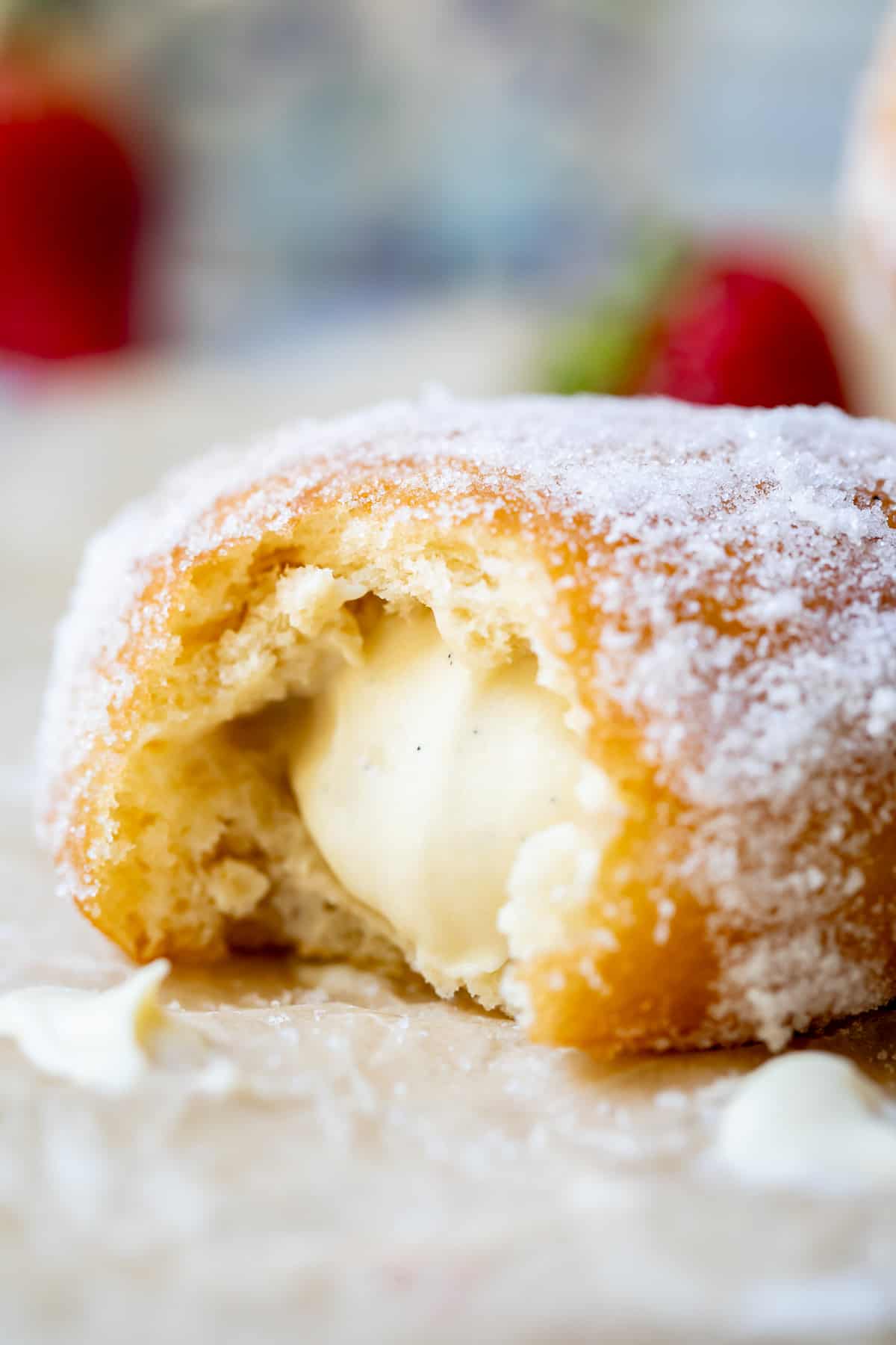 close up of a Bavarian cream donut with a bite taken from it, showing the cream in the center.