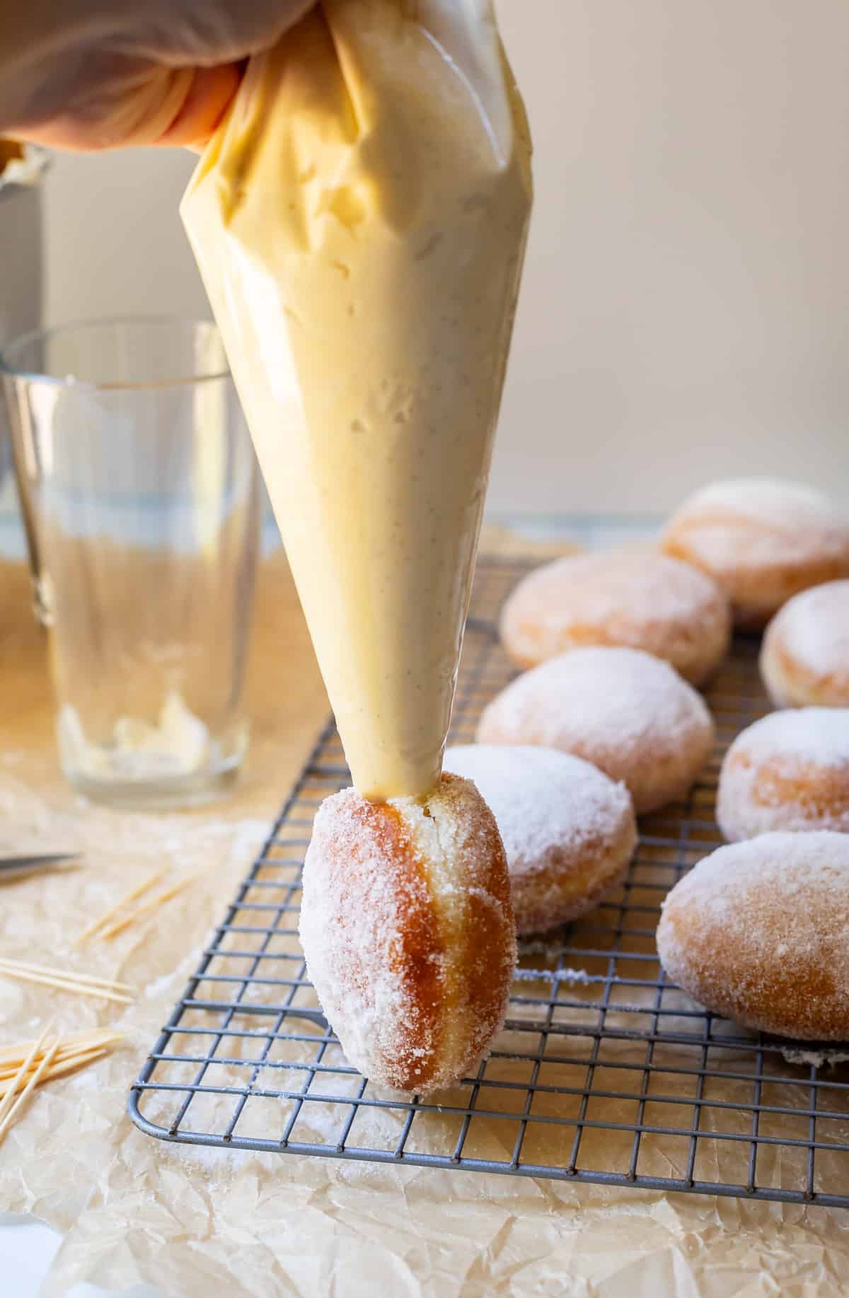 round donut on end with cream filled piping bag piping the cream into the donut.