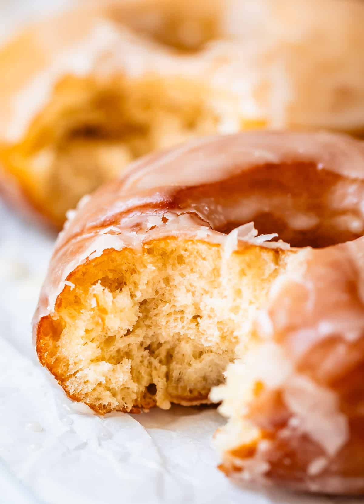 close up of a donut with a bite in it, showing the fluffy, yeasty insides.