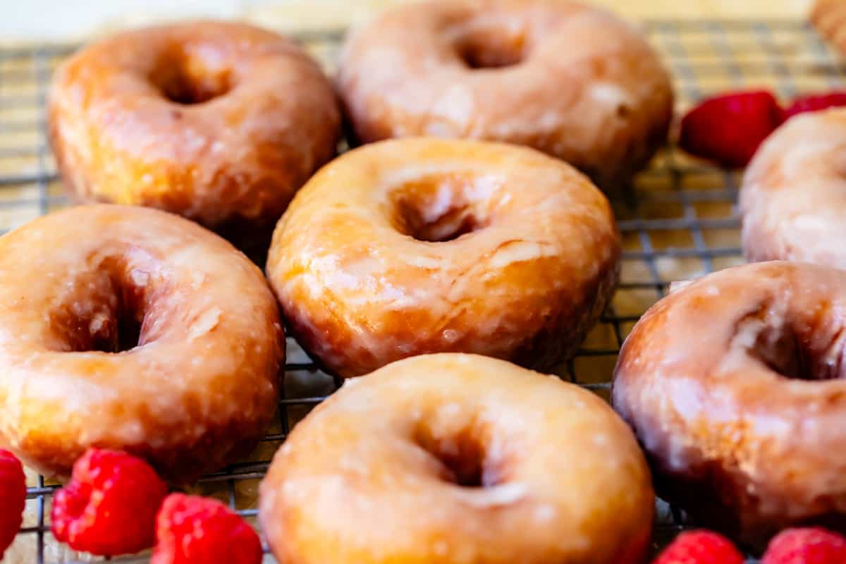 several perfectly fried and glazed homemade donuts on a cooling rack.