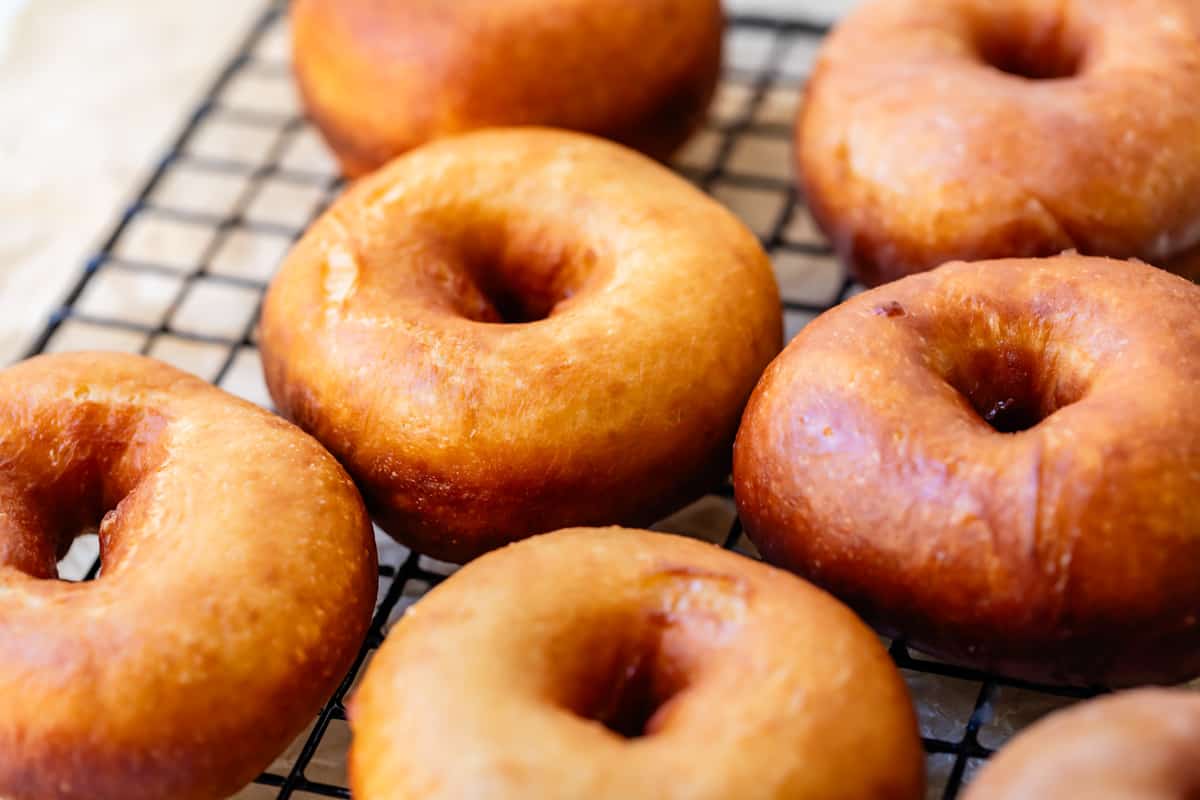 close up of perfectly fried donuts without any glaze on them sitting on the cooling rack.