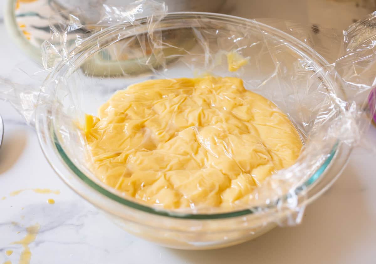 glass bowl filled with Crème Pâtissière with plastic wrap pushed directly on top to prevent film.