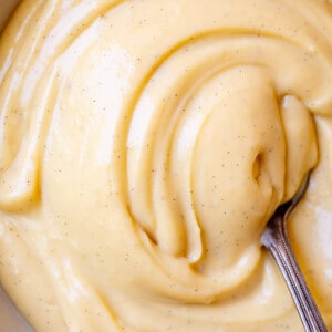 bowl of creamy, vanilla bean flecked Crème Pâtissière being swirled by a spoon.
