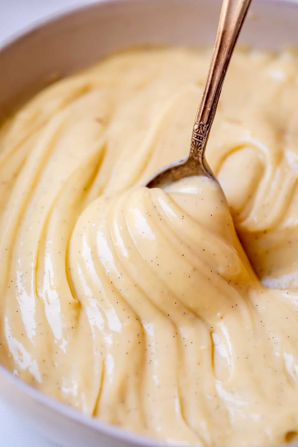 spoon lifting up as if to pour out pastry cream, but the cream is thick and sticks to the spoon.