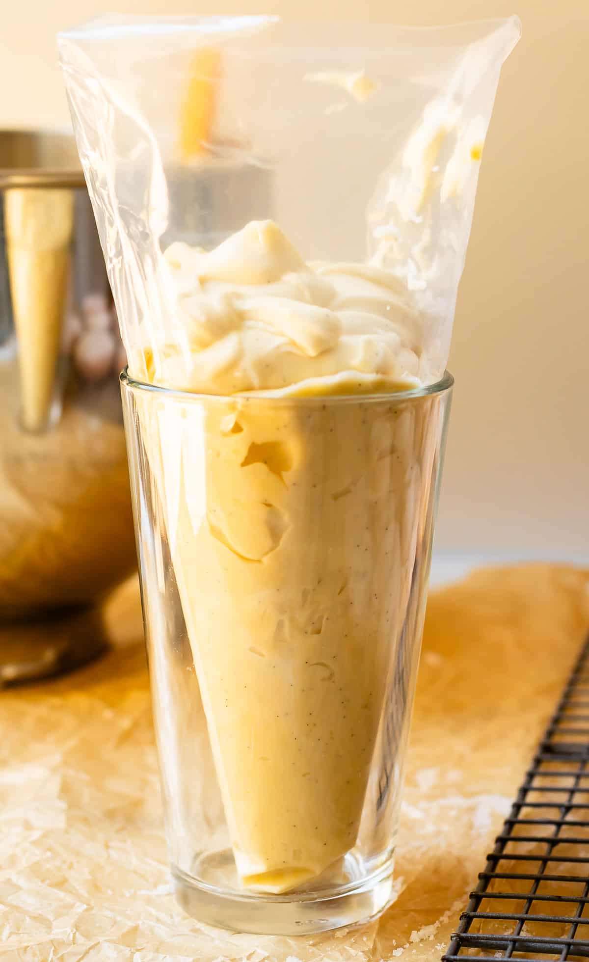 a drinking glass holding up a pastry bag that is filled with homemade pastry cream.