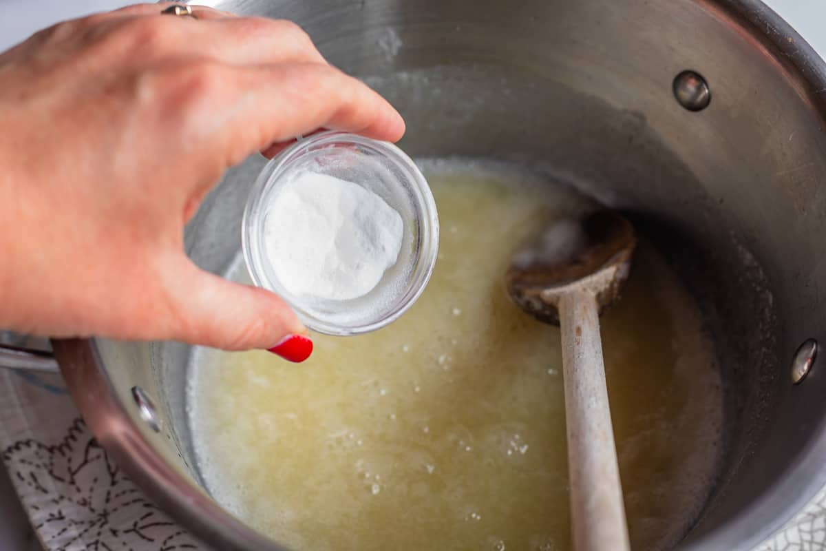 Adding baking soda to a pot of boiling liquid.