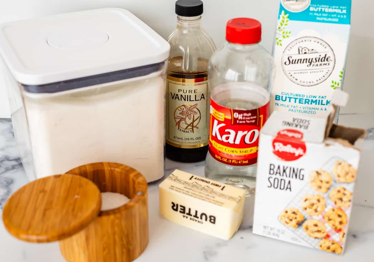 Sugar, vanilla, karo syrup, buttermilk, baking soda, butter, and salt on a white countertop.