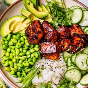 view of a whole bowl with honey sriracha salmon, rice, and toppings.