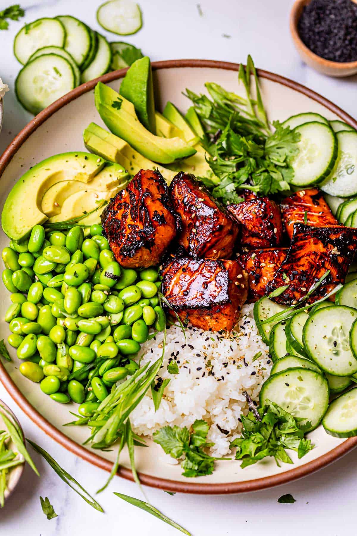 view of a whole bowl with honey sriracha salmon, rice, and toppings.