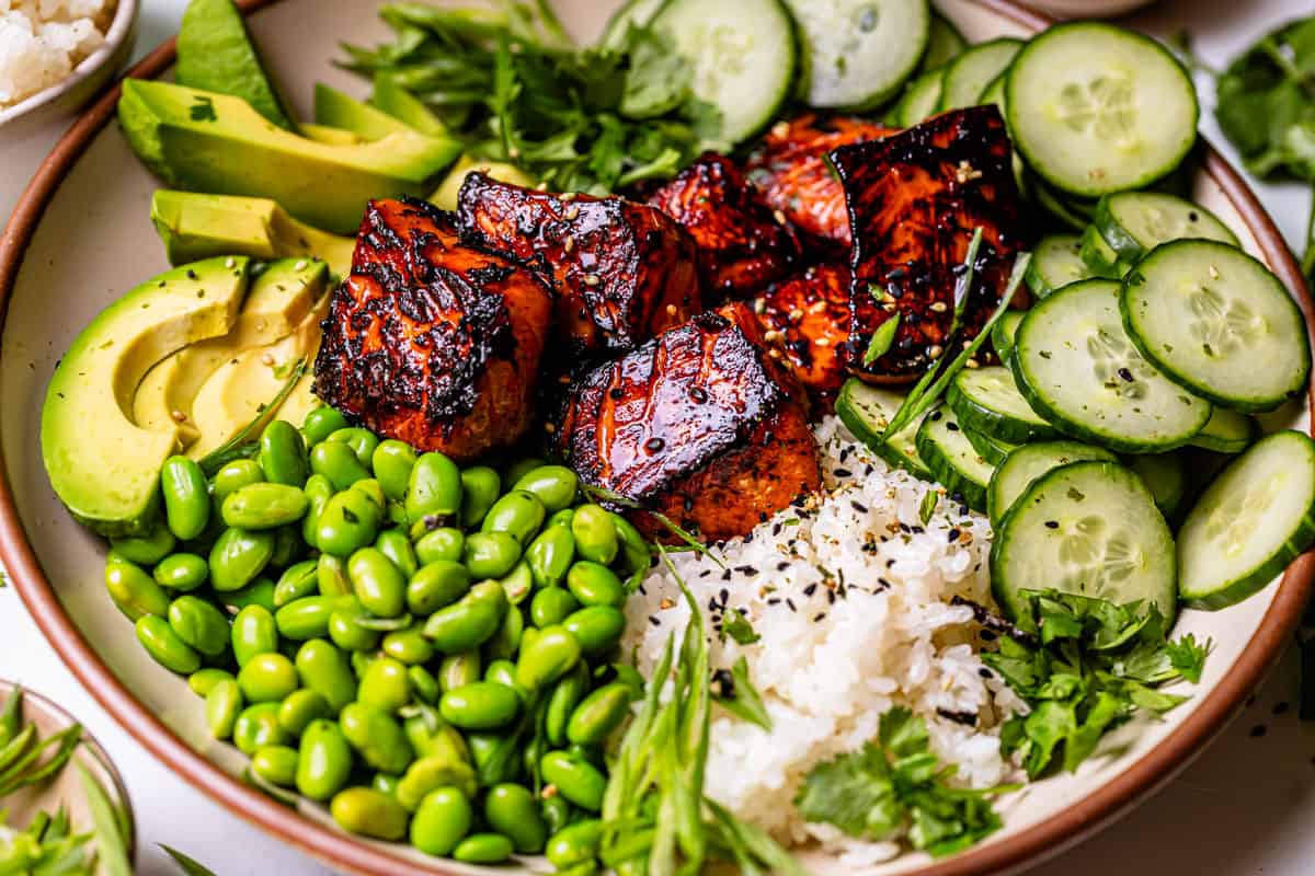 close up of a wide and deep bowl focusing on crispy salmon surrounded by toppings.