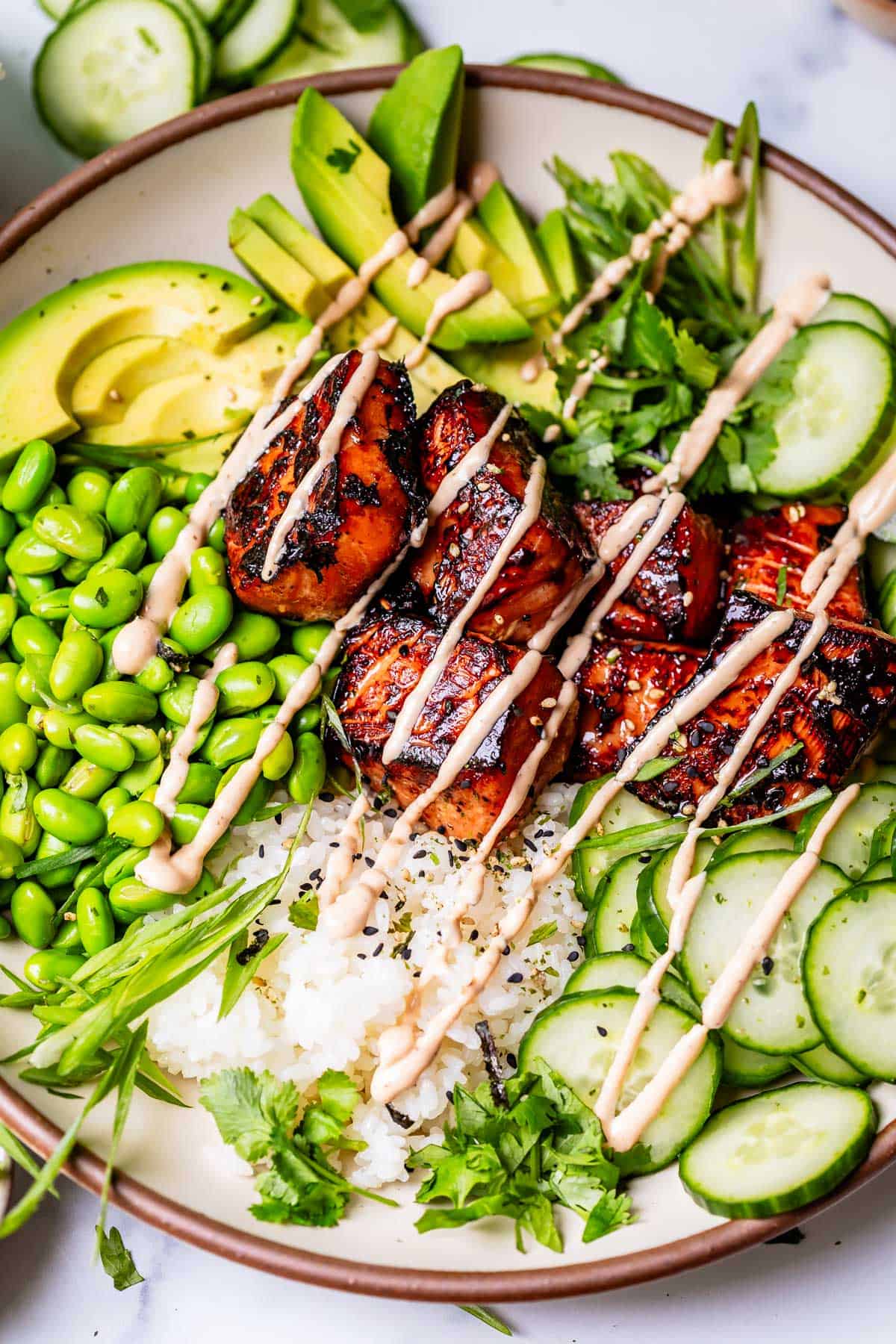 full dinner plate with sushi rice, seared honey sriracha salmon, and lots of toppings.