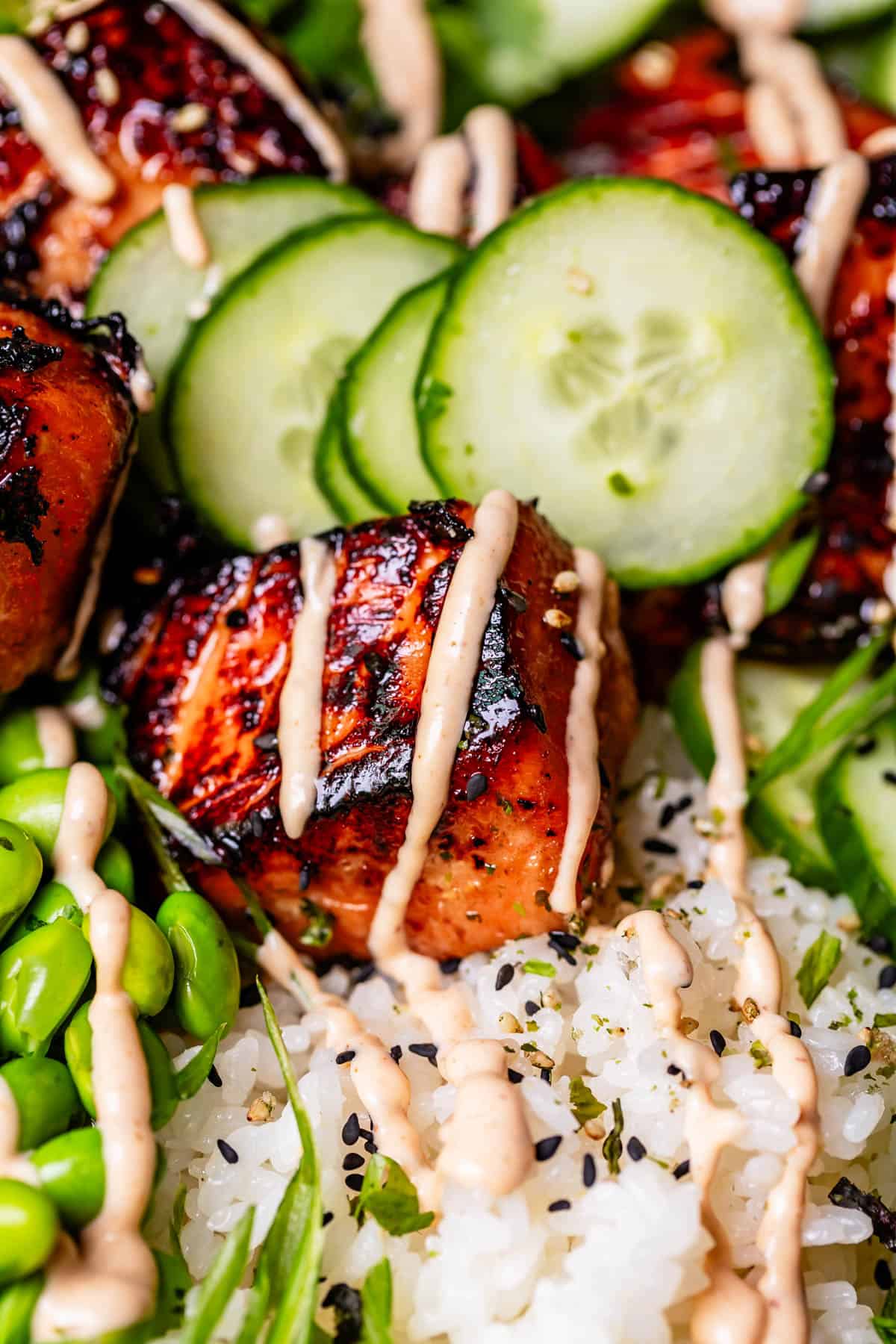 close up of one bite of crispy cooked salmon with sriracha mayo drizzled over top.