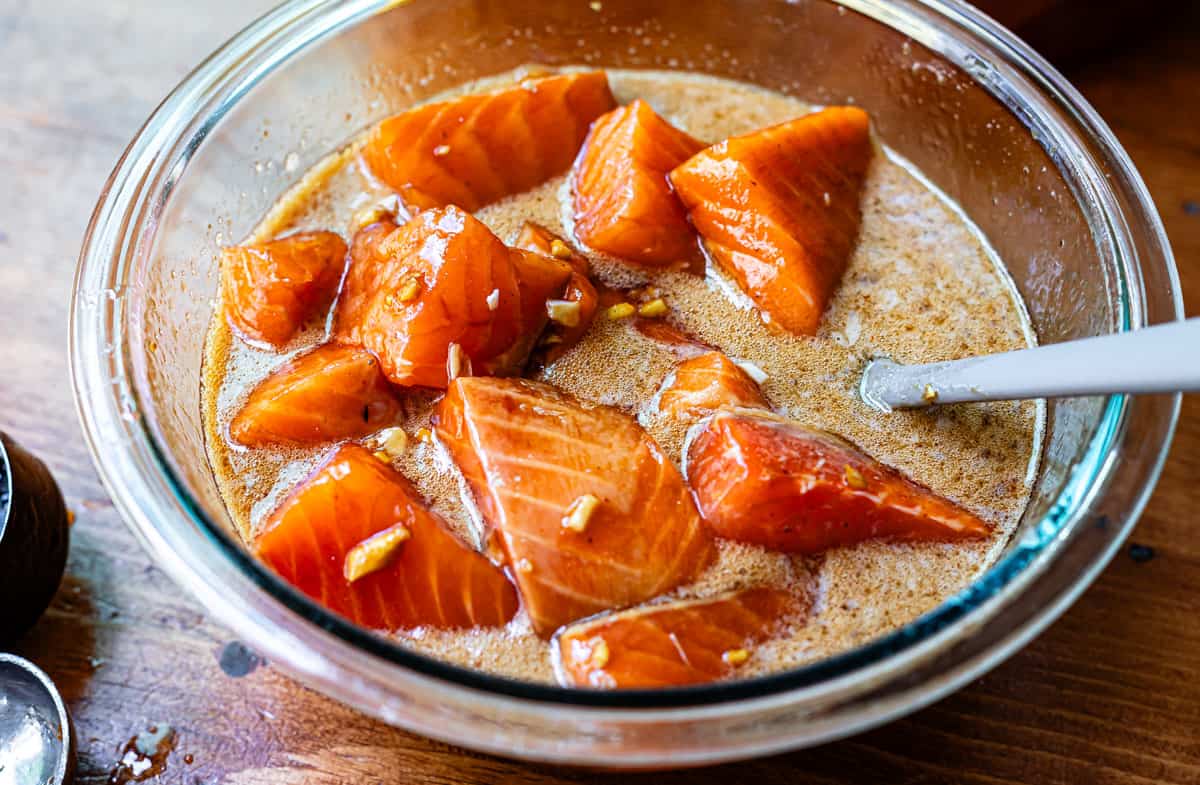 salmon marinating in a glass mixing bowl for the honey sriracha salmon bowls.