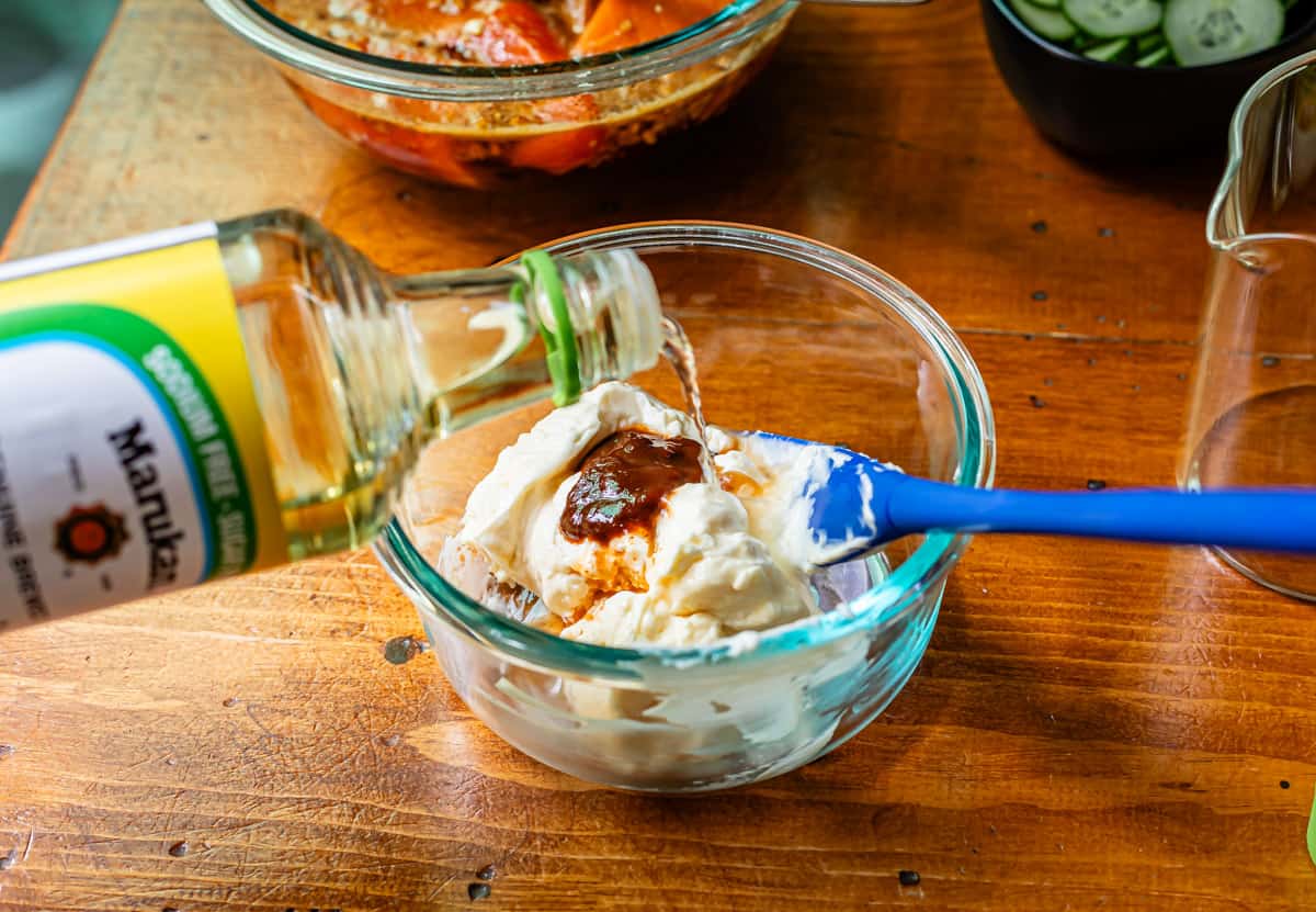 rice vinegar being poured from a bottle into a glass mixing bowl with other sriracha mayo ingredients.