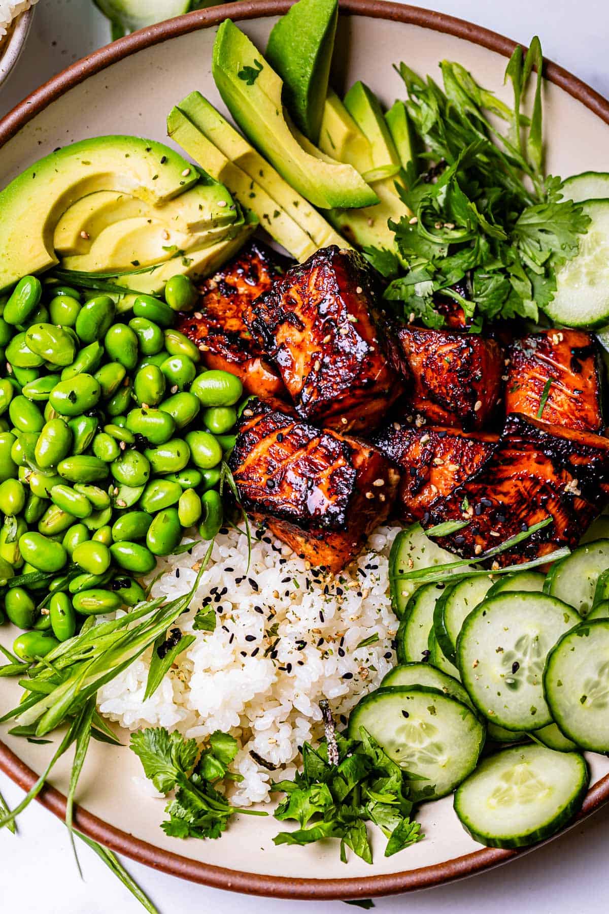 Ceramic dinner bowl with sushi rice, blackened salmon, cucumber, edamame, and more.