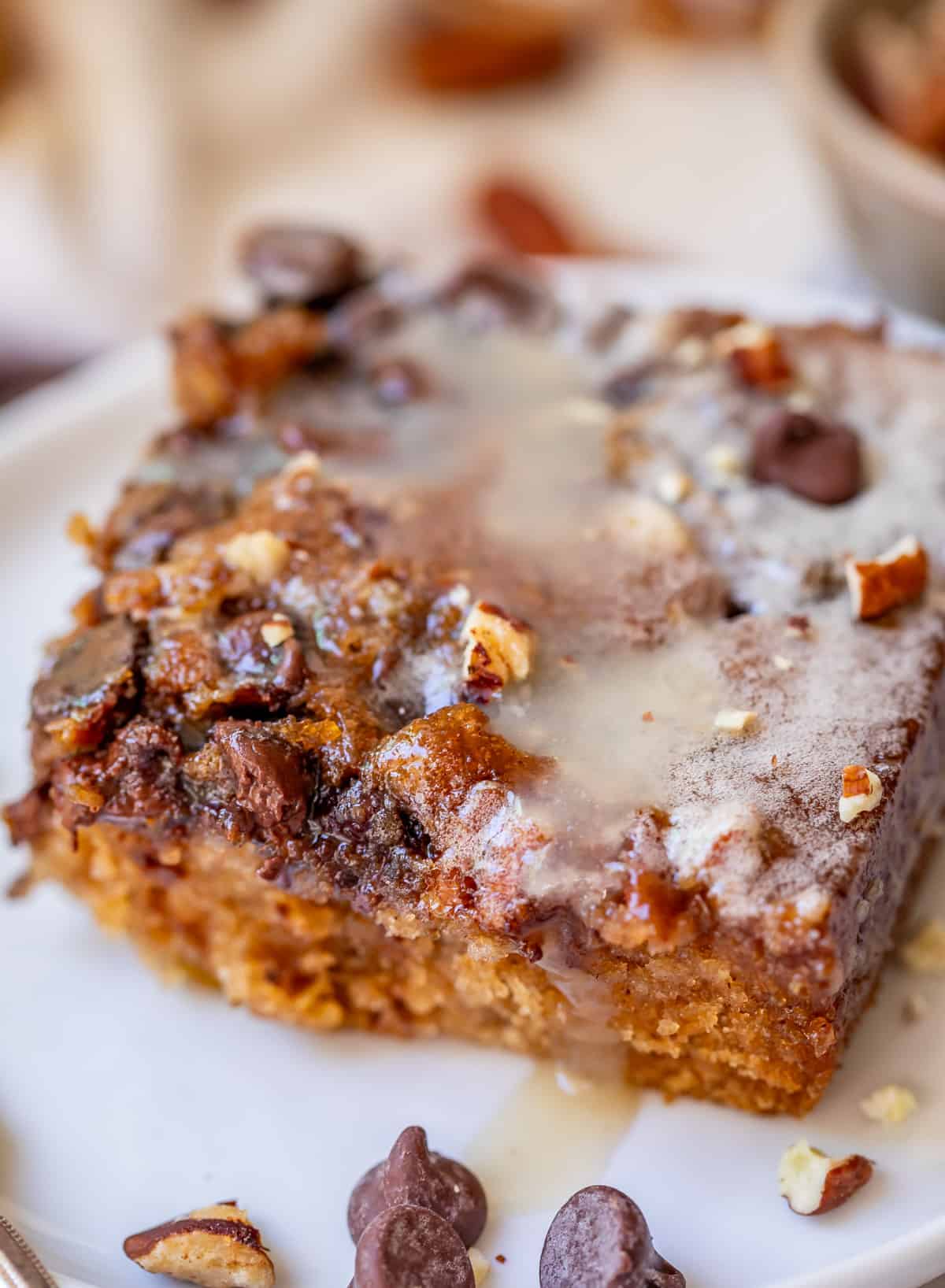 cut piece of picnic cake with drippy buttermilk glaze over crunchy topping on a white plate.