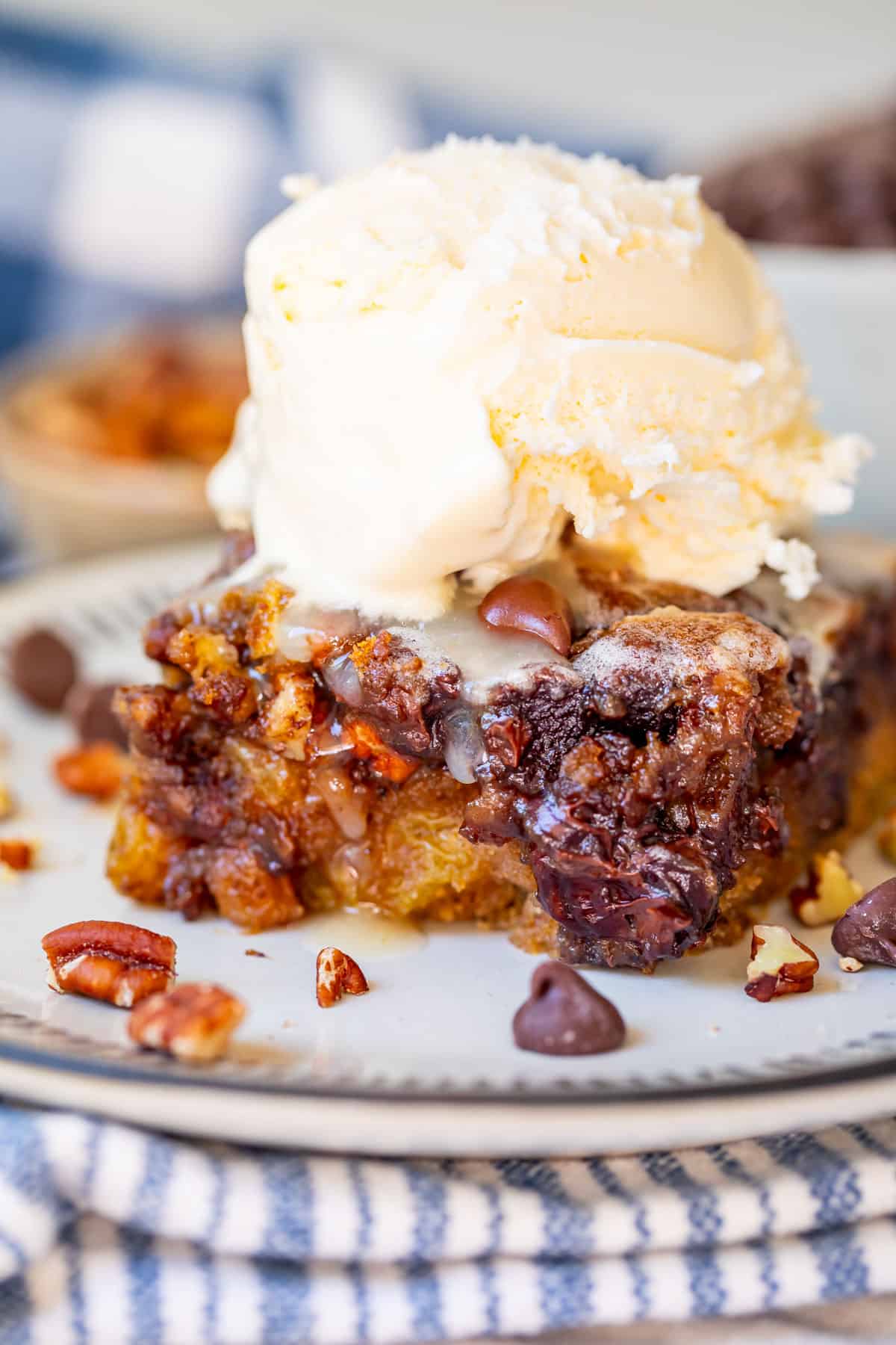 big scoop of vanilla ice cream atop a piece of picnic cake on a ceramic plate.