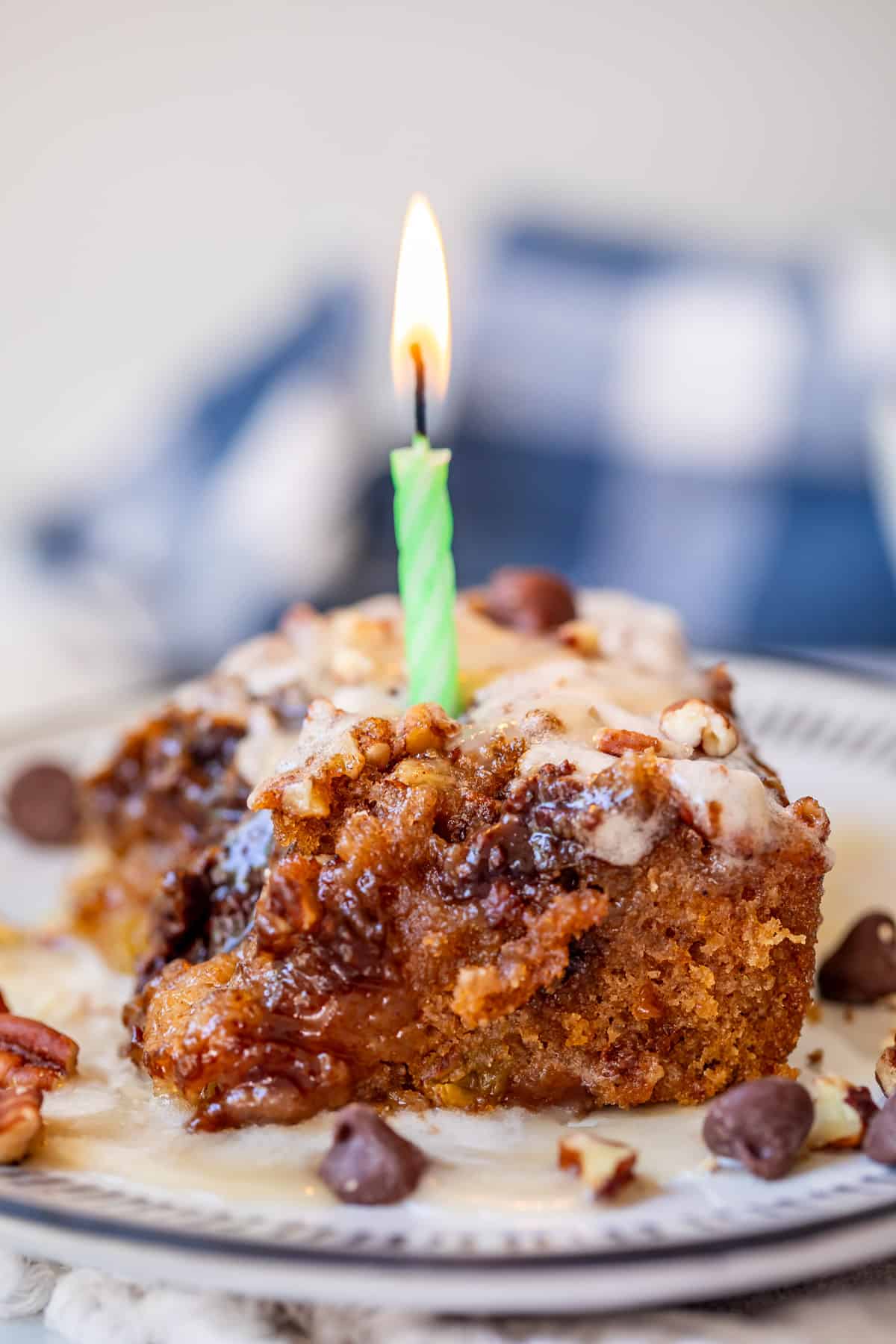 piece of picnic cake on a plate with a lit birthday candle in it representing 12th anniversary of blogging.