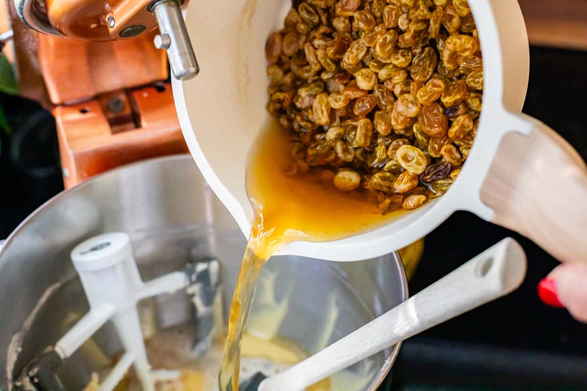 pouring the raisins with their soaking liquid into the mixer for picnic cake.