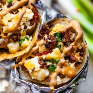 breakfast burritos wrapped in aluminum foil close up.