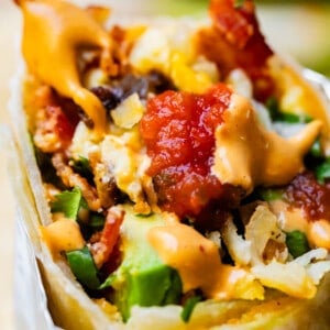 Breakfast burrito with bite out of it and salsa.