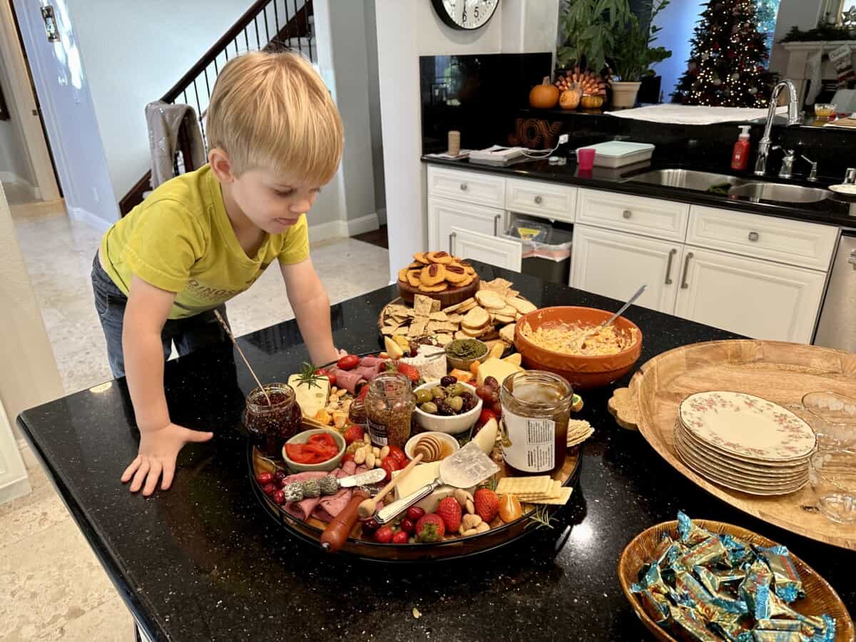 small boy leaning over charcuterie board.