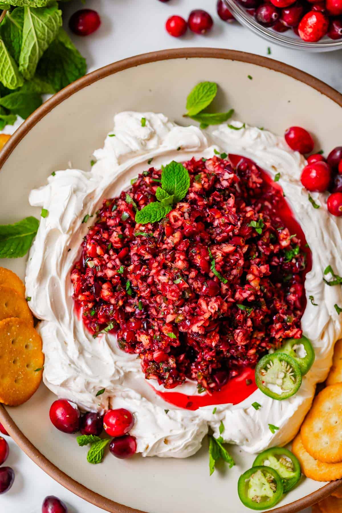 overhead shot of cranberry dip poured over whipped cream cheese with green onion as garnish.