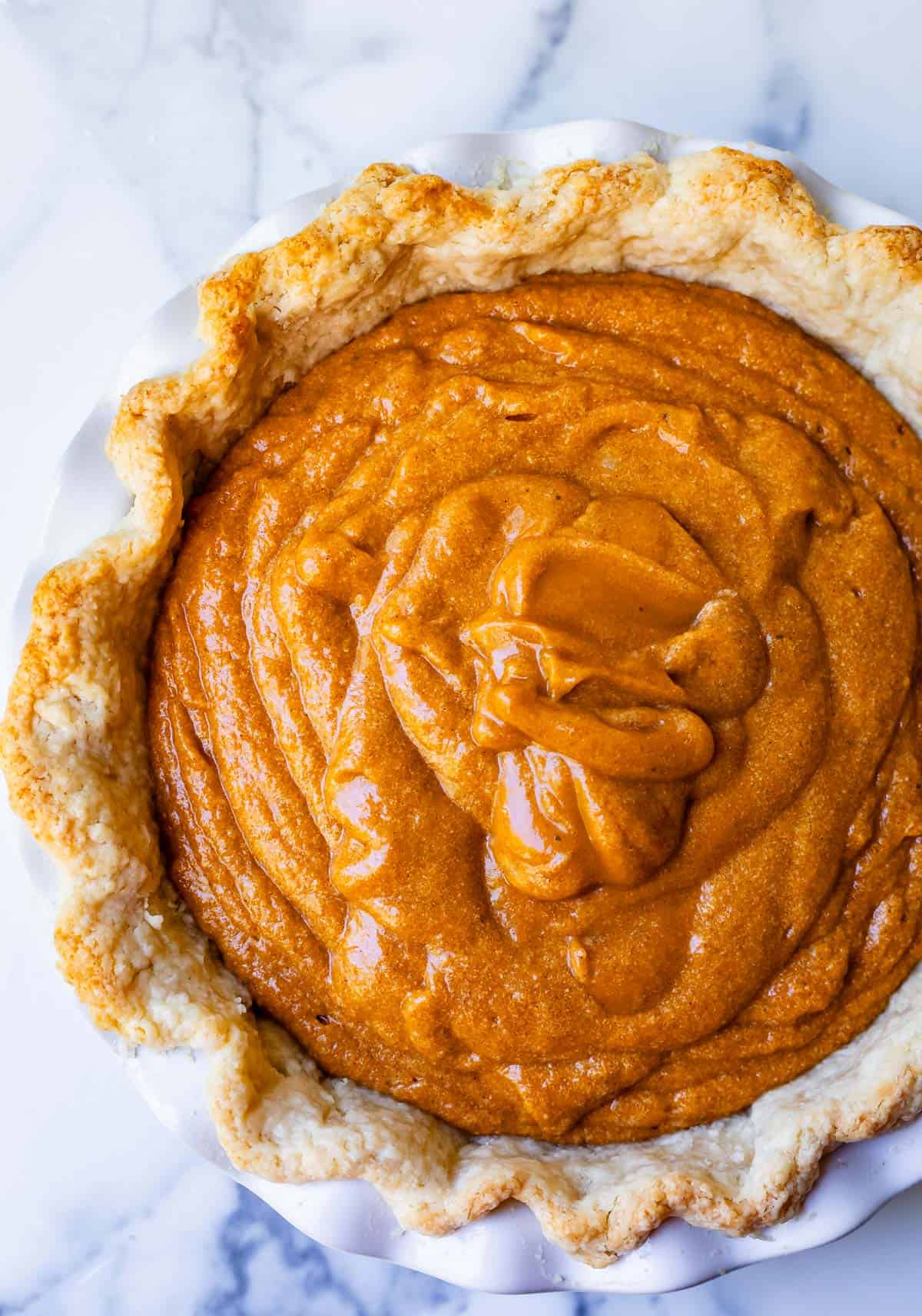 overhead shot looking down on a sweet potato pie with raw filling ready to be baked.