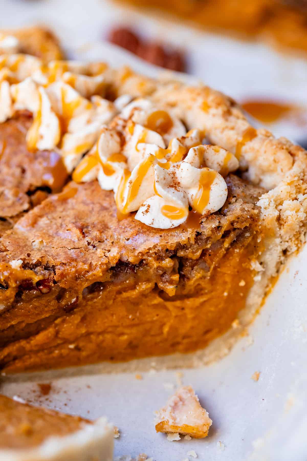 side view of pie with praline topping baked into it, with dollop of caramel whipped cream.