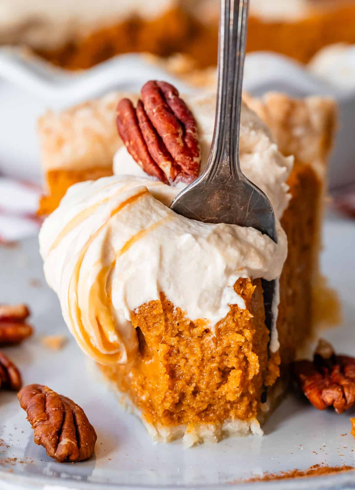 fork digging into a slice of southern sweet potato pie with a delicious salted caramel whipped cream.