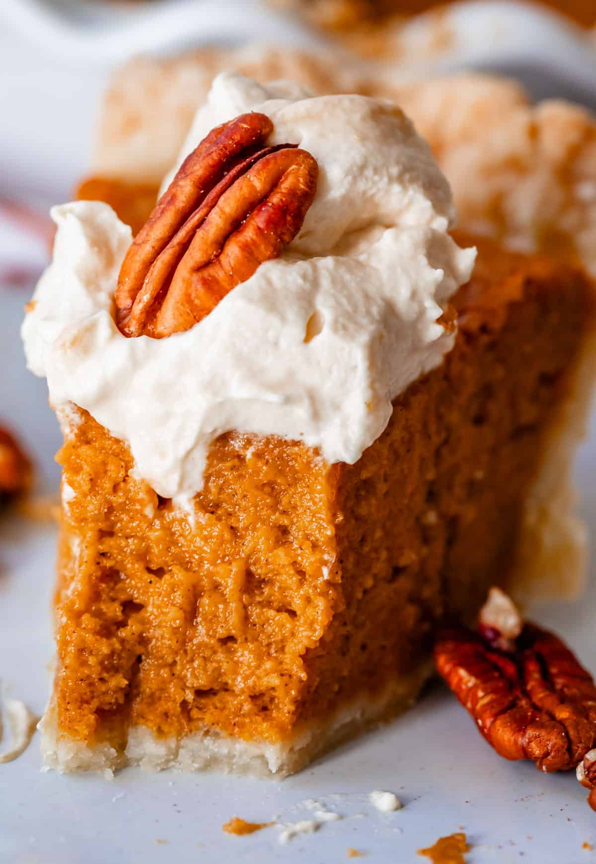 slice of sweet potato pie topped with salted caramel whipped cream with a bite taken from it.