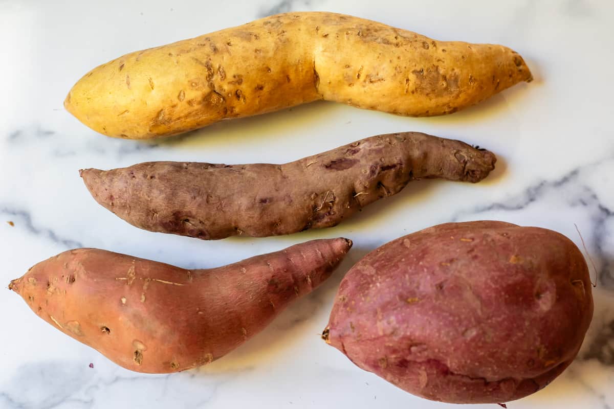 different sweet potatoes - long and skinny (one golden, one brown), 2 red skin, one long, one fat.