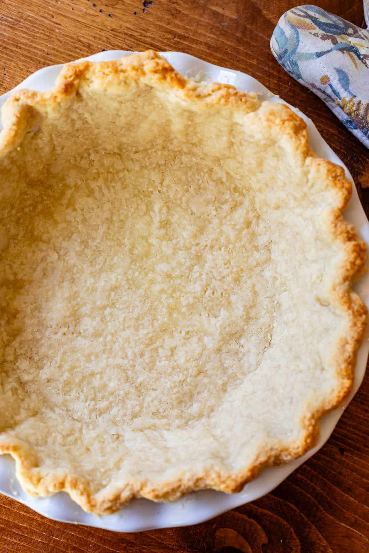 a perfectly browned par-baked pie crust in a white pie dish ready for sweet potato pie filling.