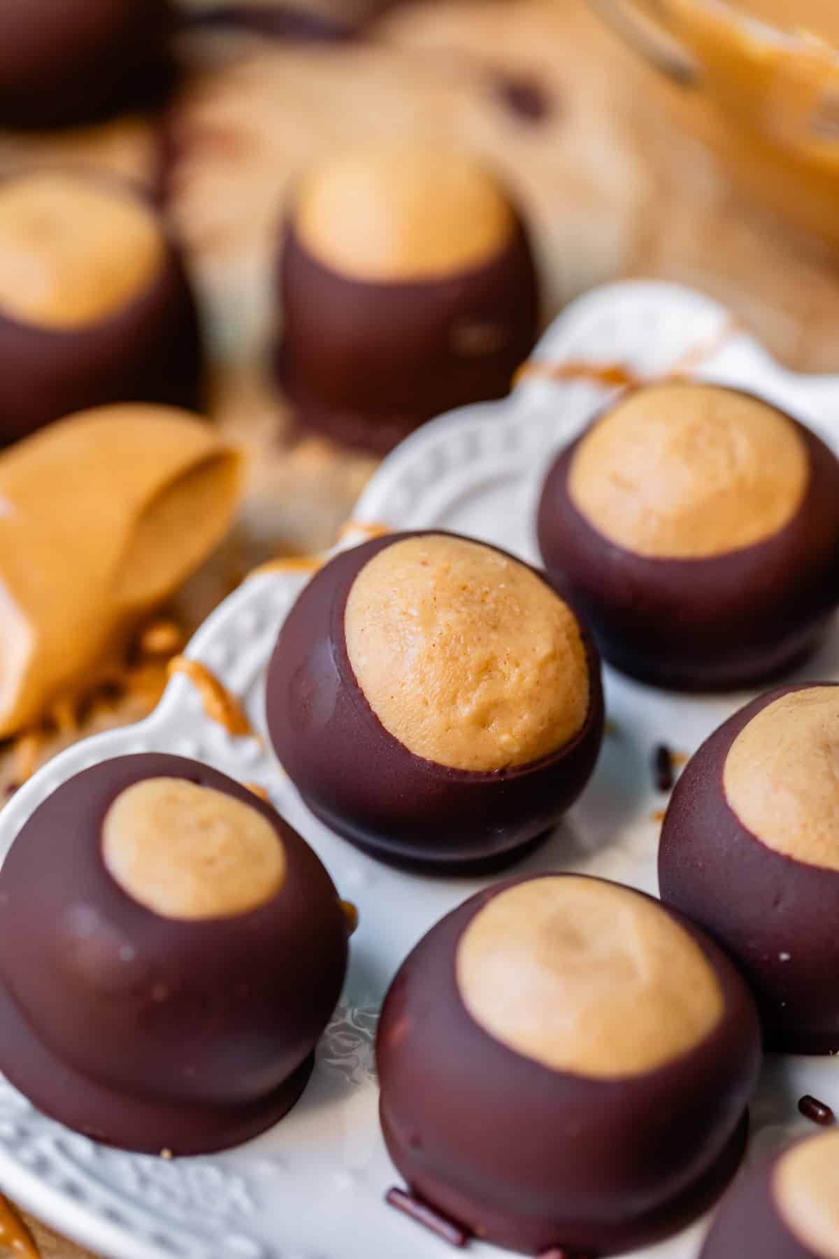 Buckeyes lined up on a white fancy plate with others in the background.
