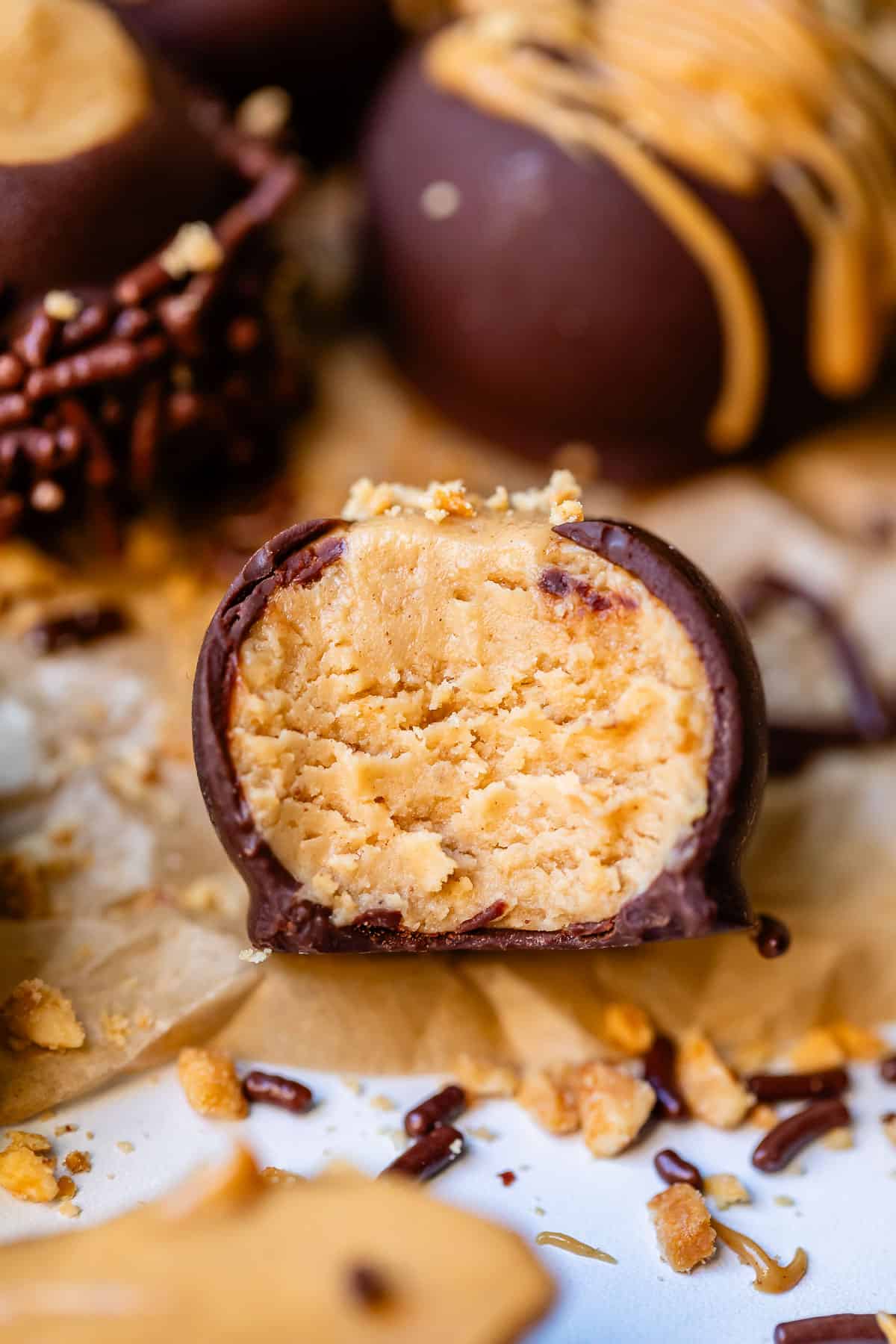 Close up of peanut butter buckeye candy with bite taken out revealing the delicious center.