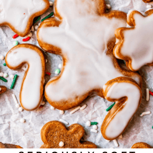 glazed gingerbread man with other cookies around, on parchment paper.