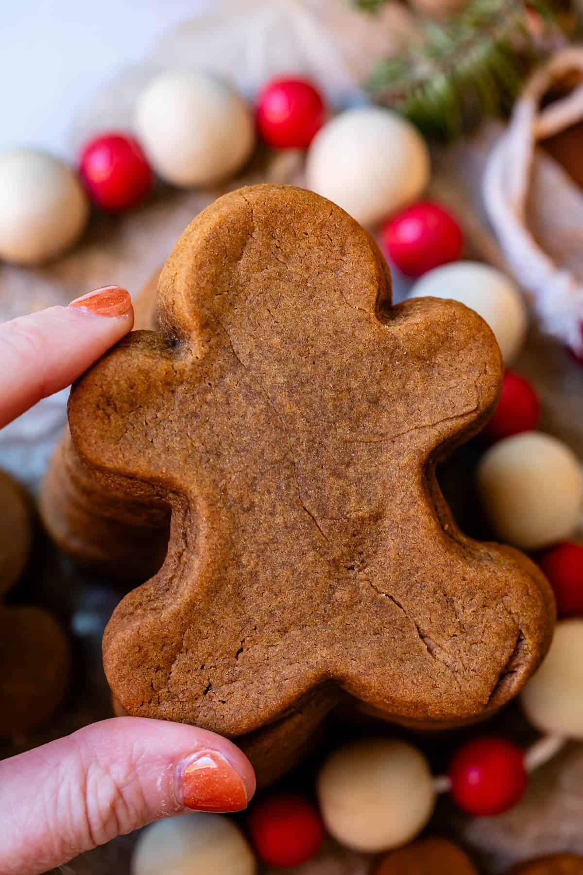 perfectly soft gingerbread man cookie at the top of a stack, being picked up by a hand on the left.