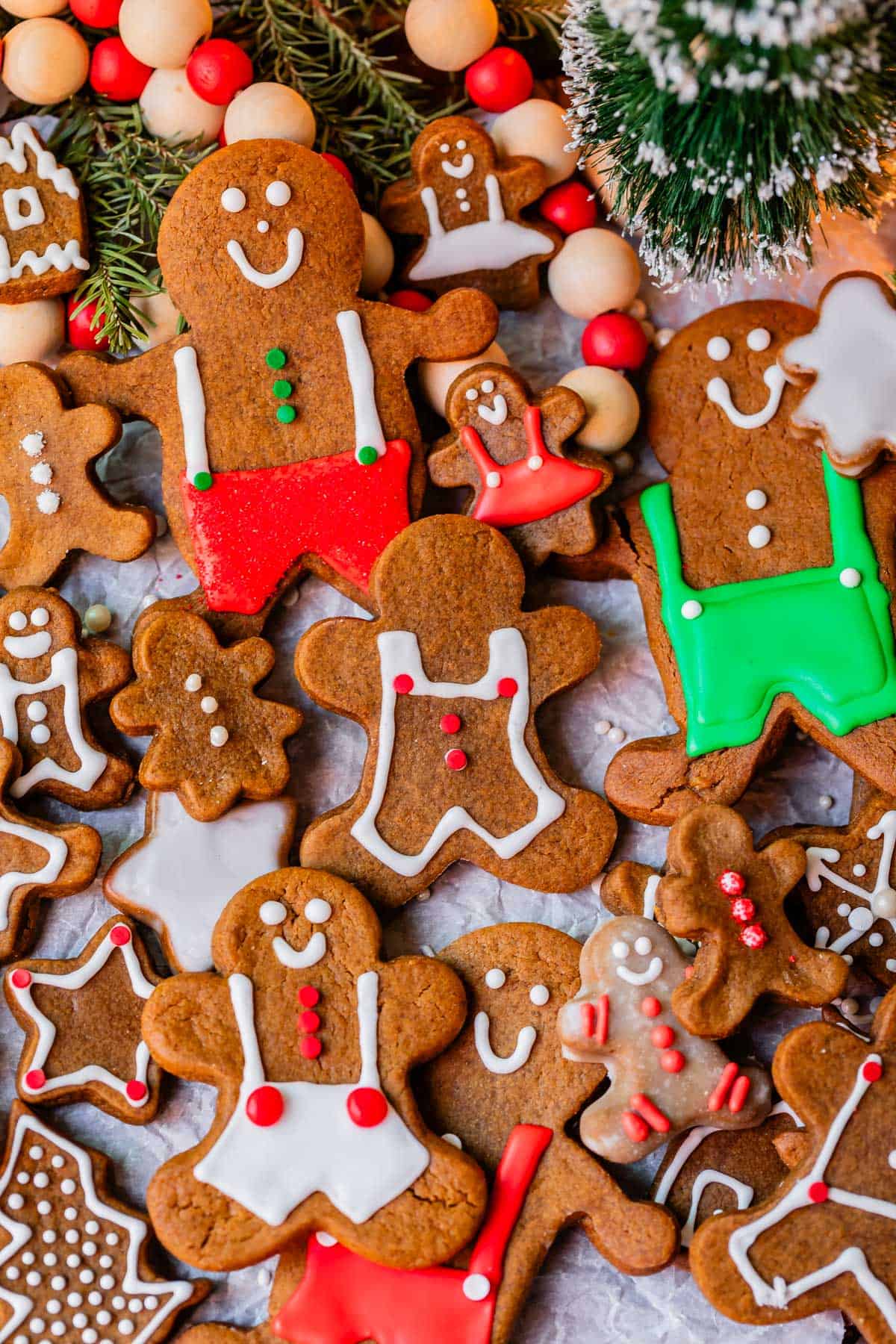gingerbread cookies with red white and green decorations on parchment paper with christmas tree.
