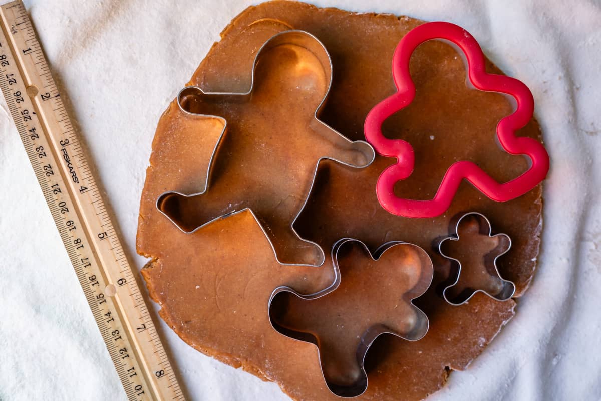 rolled out dough with 4 different sizes of gingerbread men cookie cutters on top.