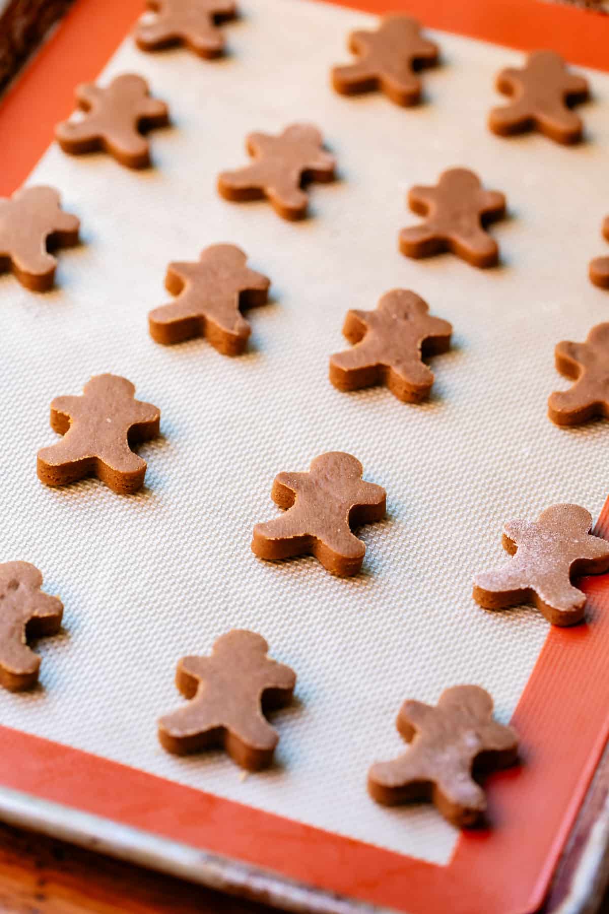 a baking sheet topped with a silpat and filled with tiny cut out gingerbread men.