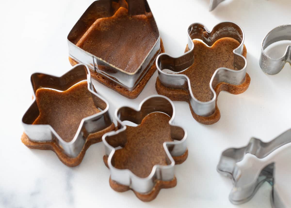 4 cut out and baked gingerbread cookies with the cutters on top to show they didn't spread.