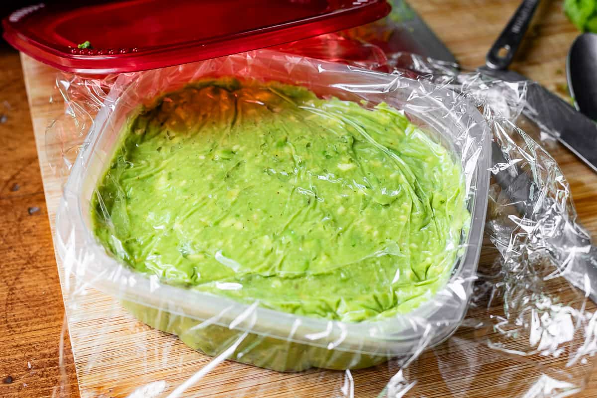 plastic wrap pressed directly on top of the juice topped guacamole in the container.