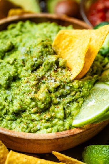 close up showing detail of guacamole with flakes of salt and 2 chips perfectly scooping into it.