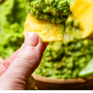 finger and thumb holding a chip with guac on it and text stop messing up guacamole try this easy recipe.