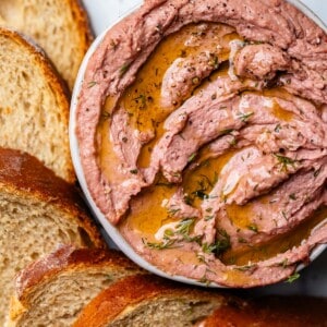 Liver pate in bowl surrounded by slices of rye bread.
