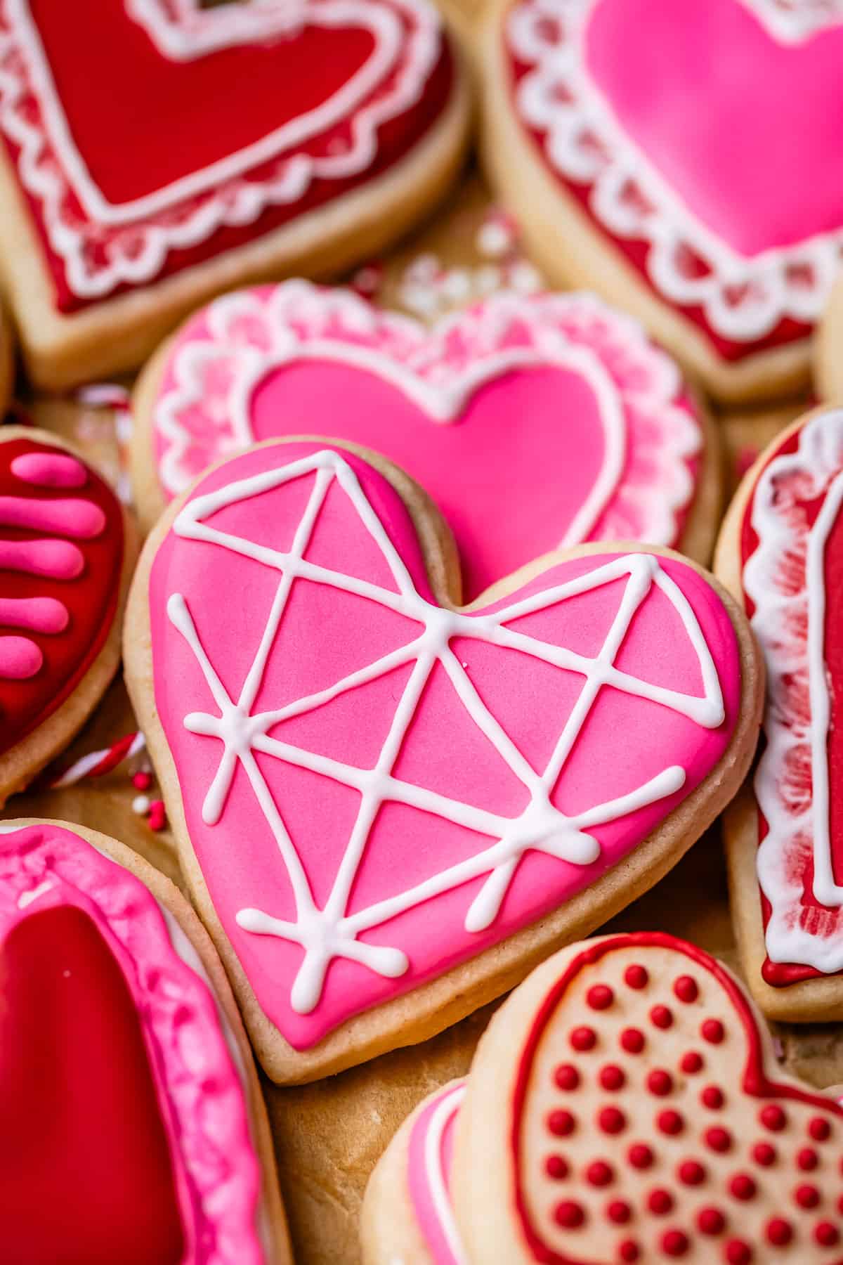 heart shaped sugar cookie with pink royal icing and white details.
