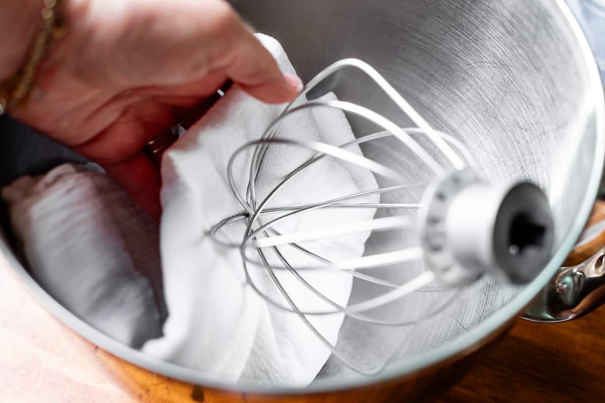 a tea towel dampened with vinegar wiping mixing bowl and whisk to remove all grease.